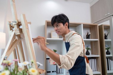 A young artist passionately painting in a home studio showcasing creativity and inspiration in a modern setting. clipart