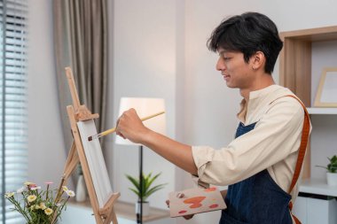 Genç bir sanatçı, ilham dolu modern bir ev stüdyosunda tutkuyla bir resim yapıyor..