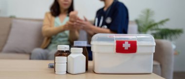 Bakıcı, yaşlı bir hastanın semptomlarını kontrol sırasında değerlendirir ve şefkatli bakımın önemini vurgular..