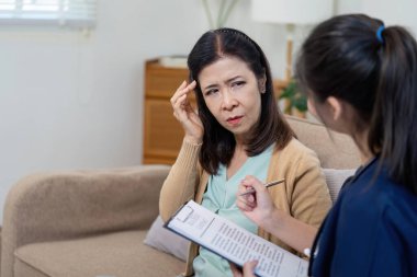 Bakıcı, sağlık hizmetleri etkileşimlerinin önemini vurgulayan bir sağlık kontrolünde yaşlı bir hastanın semptomlarını değerlendirir.