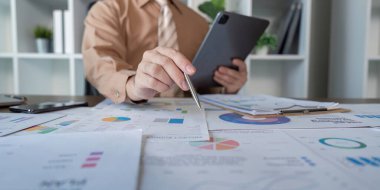 Bir iş toplantısında dijital raporları inceleyen profesyonel bir gözlemci analitik ve strateji tartışmalarına odaklandı.