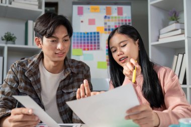 Bir tasarım ekibi, stratejik bir toplantı projesinin sonuçlarının iyileştirilmesi sırasında renk grafikleri ve grafikleri üzerinde işbirliği yapar..