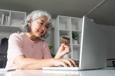 Son sınıf öğrencisi bir kadın, rahat bir ofis ortamında kredi kartını kullanarak online alışveriş yapmaktan hoşlanıyor..