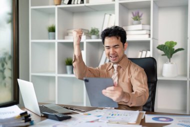 Bir profesyonel olarak çekilen neşeli bir iş başarısı, canlı bir ofiste dijital bir başarıyı kutluyor..