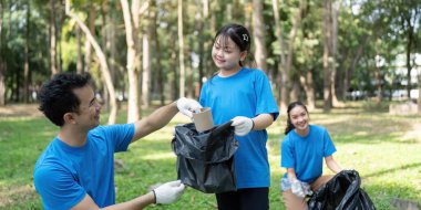 Gülümseyen bir kız, babasının çöp toplamasına yardım ederken, anne de çöp torbalarıyla ilgilenerek, kamu hizmetinde aile içi ilişkinin önemini vurguluyor..