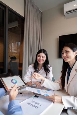 Dijital tablet kullanarak yıllık raporu tartışan ve gözden geçiren iki kendine güvenen kadın profesyonel, modern ofis ortamında görüşlerini paylaşıyor..