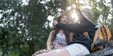 İki kadın, sevgi dolu bir çift, birbirine gülümseyen bir kayanın üzerinde oturuyorlar. Güneşli, güzel bir bataklıkta yürüyüş maceralarının tadını çıkarırken..