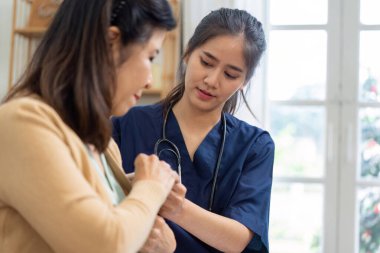 Yaşlı bir kadının kan basıncını ölçen şefkatli bir bakıcı, ev ortamında sağlık ve kişisel ilginin önemini gösteriyor..