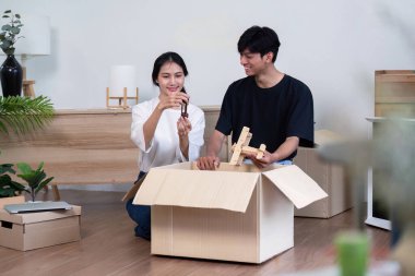 Neşeli bir çift, modern dekor ve yeşilliklerle çevrili olan eşyalarını keşfettiklerinde, yeni evlerindeki kutuları neşeyle açıyor, heyecan anlarını paylaşıyorlar..