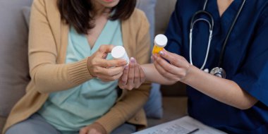 Bakıcı ve yaşlı bir hasta birlikte ilaç şişelerini gözden geçirir, evde hastalık ve sağlık yönetimi belirtilerini tartışırlar..