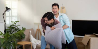 İki adam, bir çift, neşeli bir anı paylaşıyorlar. Canlı yeni evlerinde bir yastık kavgası yapıyorlar..