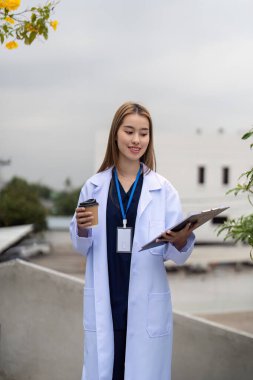 Beyaz önlüklü gülümseyen bir doktor, elinde kahve fincanı ve tablet tutarak, modern sağlık hizmetlerinde profesyonelliği ve hasta danışmanlığını somutlaştırıyor..
