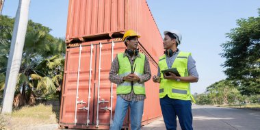 Güvenlik yelekleri ve miğferler konusunda iki profesyonel, biri tablet, diğeri ise telsiz, lojistik ve mühendislik alanında takım çalışması içeren dostane bir sohbete girişiyor..