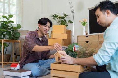 İki adam yeni oturma odalarında bitki ve dekoratif eşyalar düzenliyor. Yaratıcılıklarını ve sevgilerini sergiliyorlar..