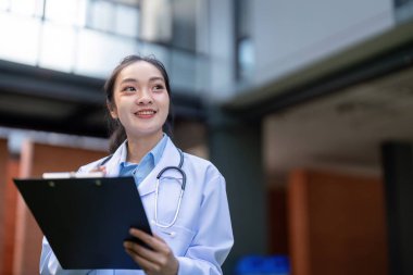 A happy doctor holds a clipboard and smiles, indicating positive engagement with patient care and professionalism in a healthcare environment. clipart