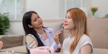 Bir güzellik komisyoncusu canlı yayında arkadaşının yüzüne makyaj yapıyor. Güzellik tekniklerini ve arkadaşlığın neşesini vurguluyor..