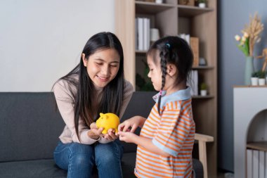 Bir anne, davet odasındaki domuz kumbarasını kullanarak kızına para biriktirmeyi zevkle öğretir..
