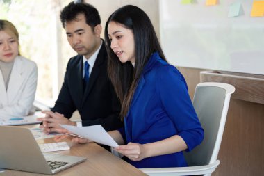 Bir sunuma katılan çeşitli bir iş ekibi, çağdaş bir çalışma alanında etkili iletişim ve analiz becerileri sergiliyor..