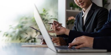 Bir avukat ve müvekkil aktif olarak yasal stratejileri tartışıyor ve parlak bir ofis ortamında dizüstü bilgisayarda belgeleri gözden geçiriyorlar..