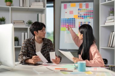 Renk seçimlerini ve proje kavramlarını tartışan farklı grafik tasarım ekibi, parlak ve modern bir çalışma alanında işbirliği yapıyor..