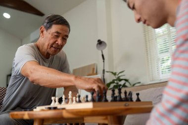 Bir baba oğluna karşı satranç hamlesi yaparken gülümserken evdeki oyun sırasında bir neşe ve bağlantı anı yakalar..