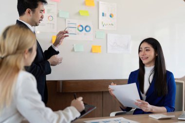 Çağdaş bir çalışma alanında işbirliği ve etkili iletişimi vurgulayan, finansal içgörüler hakkında dinamik bir tartışmaya katılan çok kültürlü bir iş ekibi.