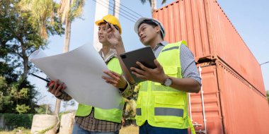 İki lojistik mühendisi, konteynır yönetimi stratejilerini proje verimliliği ve güvenliğini güvence altına alan bir inşaat sahasında tartıştı.