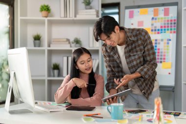 Modern ve ilgi çekici bir çalışma alanında tablet kullanırken proje fikirleri üzerinde çalışan çeşitli grafik tasarım ekibi.