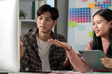 Yaratıcı bir ofis ortamında çalışırken grafik tasarım fikirleri üzerine tartışan çeşitli bir ekip.