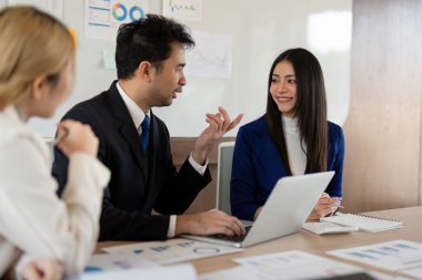 Bir kadın ve erkek profesyonel mevcut finansal stratejiler, çağdaş bir ofis ortamında takım çalışmasını teşvik ediyor..