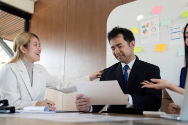 Çeşitli profesyonellerden oluşan bir grup, iş yerlerindeki çeşitli raporları incelerken, finansal stratejileri tartışan modern bir masada iş birliği yapmaktadır..