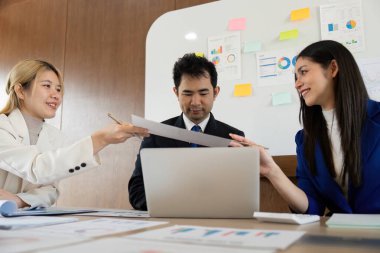 Belgeleri değiş tokuş eden, etkili iletişim ve takım çalışması sergileyen bir ekip toplantısı.