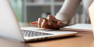 Başörtüsü içinde odaklanmış Müslüman bir kadın notlar yazar ve internet işini evden yönetirken paketleri düzenler..