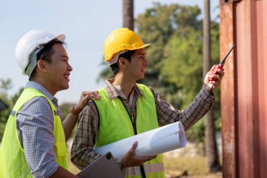 İki mühendis inşaat planlarını, takım çalışmalarını ve planlarla etkili iletişimi tartışıyor..