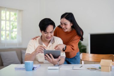 Bir çift, gelir ve bütçeyi gözden geçirmek için bir tablet kullanarak mali durumları üzerinde birlikte çalışıyor, takım çalışması ve angajman çalışmaları sergiliyorlar..