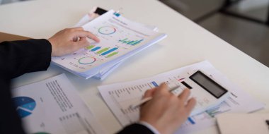 Bir mali analist raporları değerlendirir ve mali verileri izlemek ve hesaplamalar yapmak için bir hesap makinesi kullanır.