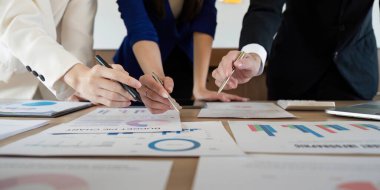 Bir iş ortamında finansal belge ve grafikleri analiz eden çeşitli profesyonellerin elleri yakın plan görüntüsü.