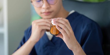 Kendini tıp fakültesine adamış bir öğrenci, ilaç bilgisinin çalışmalarındaki önemini vurgulayan bir ilaç şişesini yakından inceler..