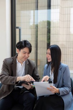 Profesyonellerden oluşan çeşitli bir ekip işbirliği içinde, proje belgelerini gözden geçiriyor ve şık bir ofis ortamında stratejileri analiz ediyor..