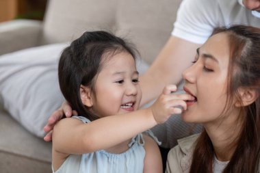 Genç bir kız annesini mutlu bir şekilde besliyor. Sevgisini gösteriyor ve samimi bir aile ortamında eğlenceli etkileşimler kuruyor..