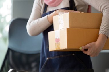 Önlüklü biri iki paket taşıyor, online bir iş ortamında nakliyeye hazır..