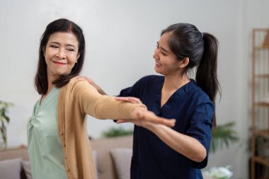 Bakıcı yaşlı bir hastaya kolunu uzatarak fiziksel aktiviteyi ve sağlığı teşvik eder..