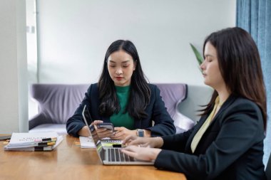 İki kadın takım çalışması yapıyor, finansal verileri analiz ediyor ve çağdaş bir çalışma alanında stratejileri tartışıyorlar..