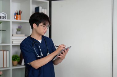 Bir tıp öğrencisi, hasta bakımına ve profesyonelliğe olan bağlılıklarını yansıtan önemli bilgileri bir tablete yazar..