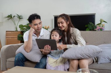 Bir aile tablet etrafında toplanıyor, kızları meşgul ve heyecanlı, sevgi ve beraberlik gösteriyorlar..