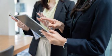 İki kadın finansal analiz, takım çalışması ve modern ofis ortamında etkili iletişim üzerine odaklanıyor..