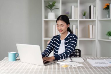 Genç bir kadın, faturalarını ve faturalarını neşeyle gözden geçirir. Mali durumuyla ilgili olumlu bir yaklaşım sergiliyor..