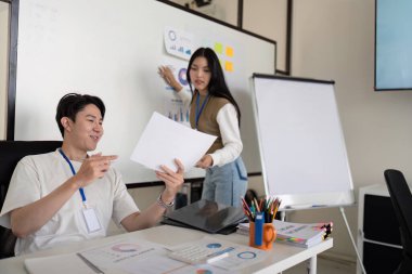 Mali belgeleri incelerken bir finans analisti, bir meslektaşının vergi indirimleriyle ilgili görsel veriler sunması nedeniyle sohbetten keyif alıyor.