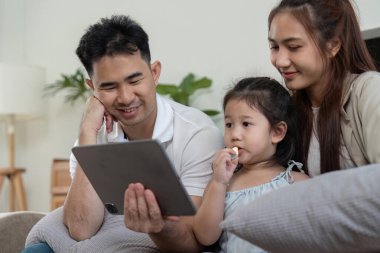 Bir aile battaniyenin altında sıcacık bir anın tadını çıkarır, birlikte tablet izleriz, sıcaklığı ve birlikteliği ön plana çıkarırız..