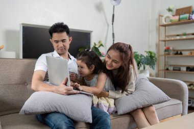 Üç kişilik bir aile bir tabletle meşgul, gülümsemelerini ve patlamış mısırlarını rahat bir oturma odasında paylaşıyorlar..